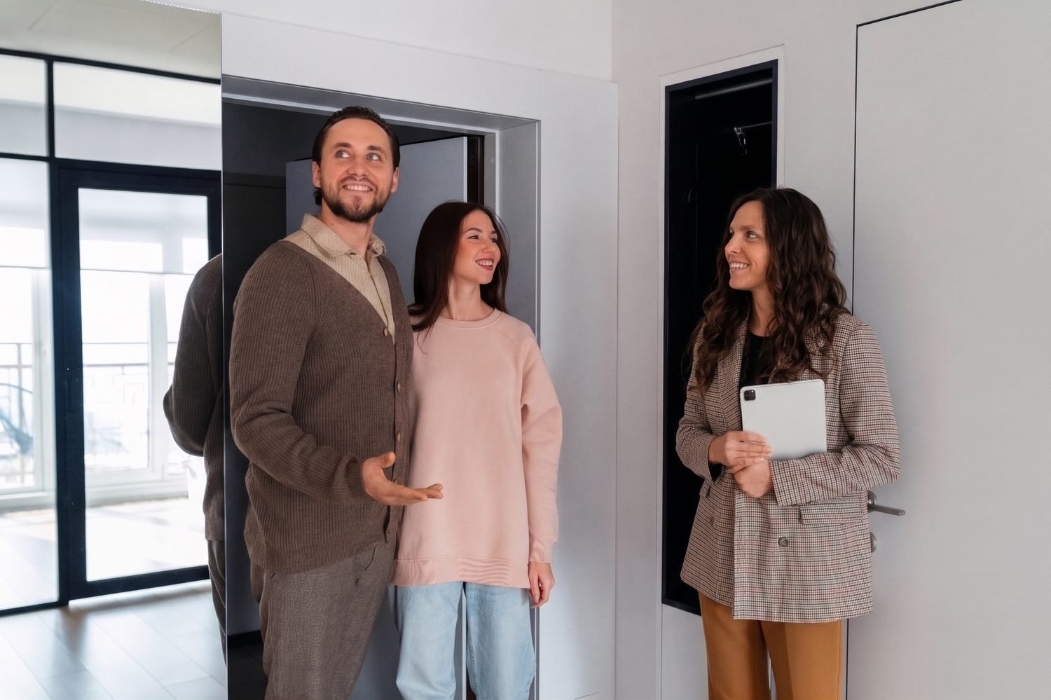 A couple touring a home with their real estate broker holding a tablet